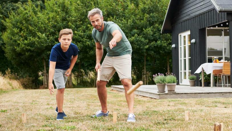 Far og søn spiller Kongespil foran sommerhus