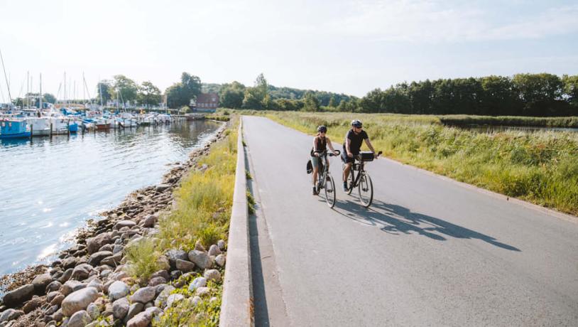 Ein Pärchen fährt Fahrrad über dem Damm von Kalvø