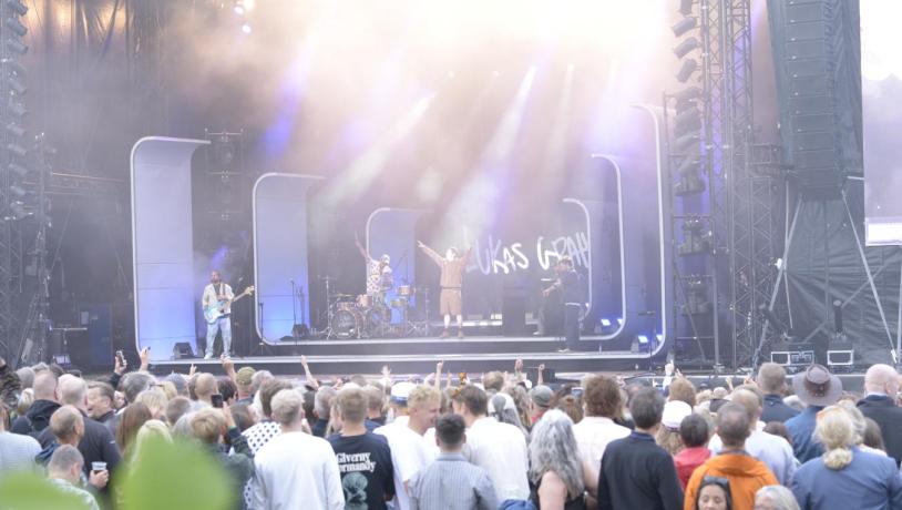 Publikum står foran scenen og nyder koncerten.
