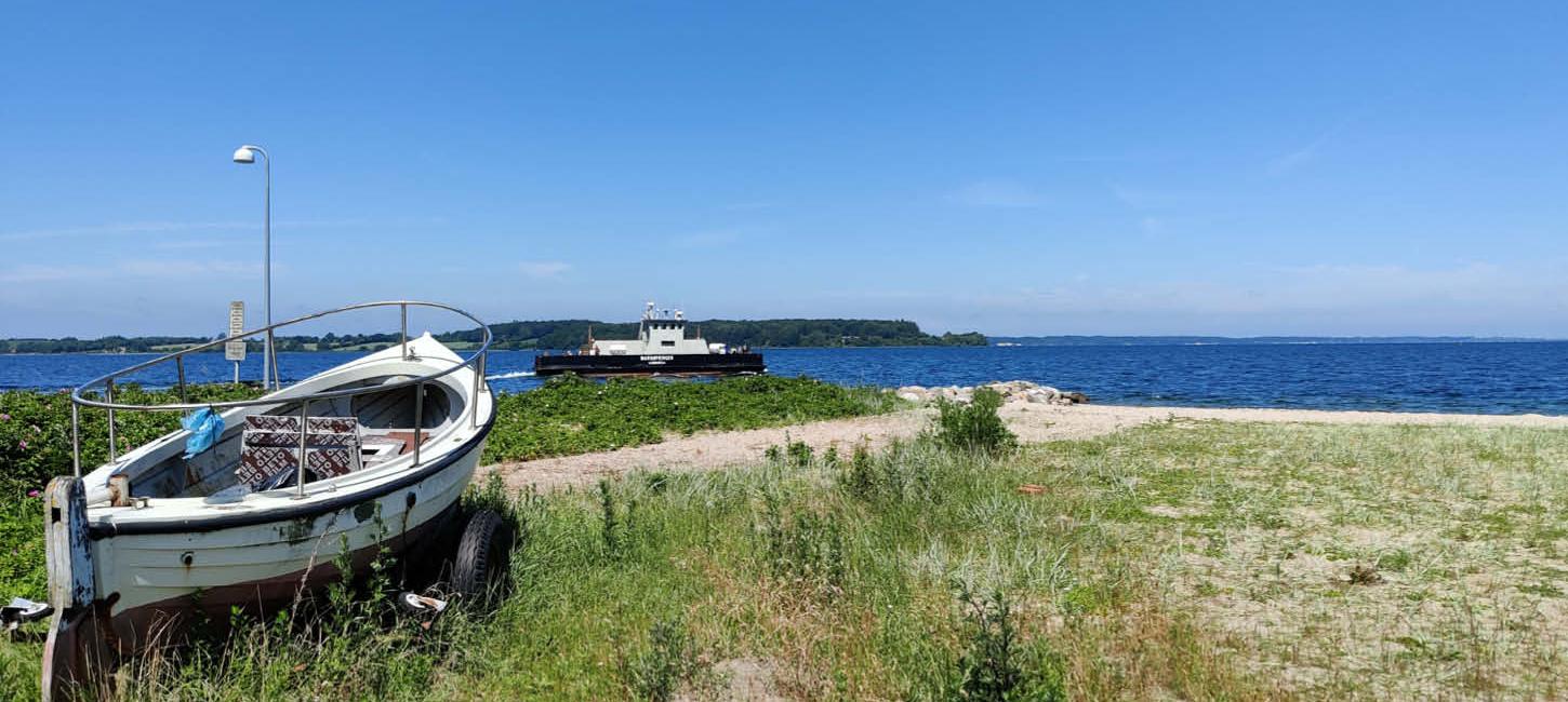 Barsø - Boot am Strand und Fähre im Hintergrund