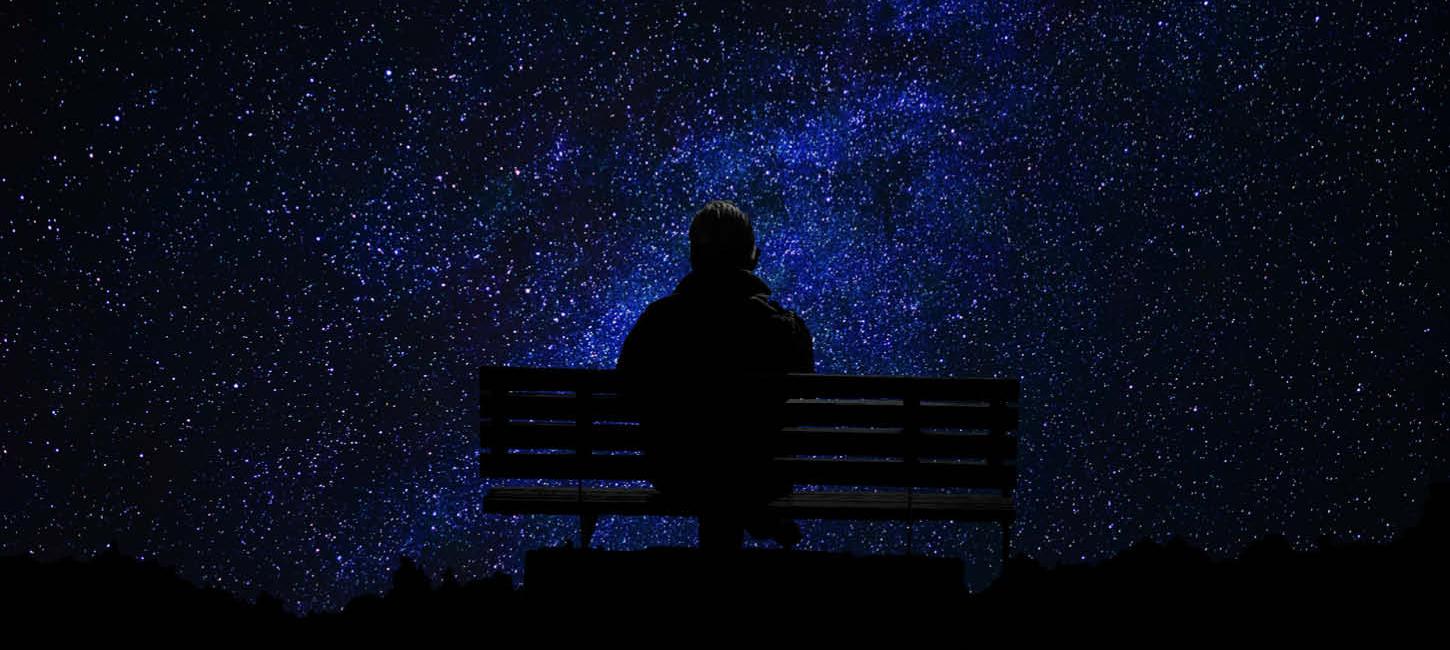 Mørkevandring - person på bænk kigger på en himmel fyldt med stjerner