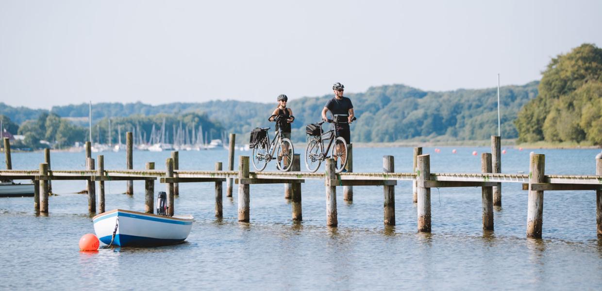 Ein Pärchen mit Fahrrädern auf der Brücke am Genner Strand