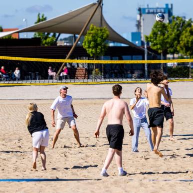 Junge Menschen spielen Volleyball mit einander am Strand von Aabenraa