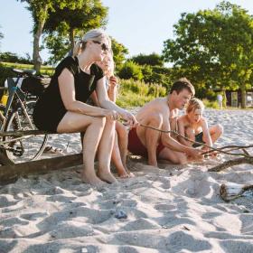 Familie am Strand mit Lagerfeuer und Fahrrädern