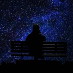Mørkevandring - person på bænk kigger på en himmel fyldt med stjerner
