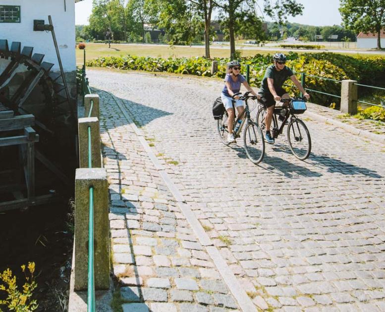 Pärchen fährt Fahrrad an der alten Schlossmühle in Aabenraa
