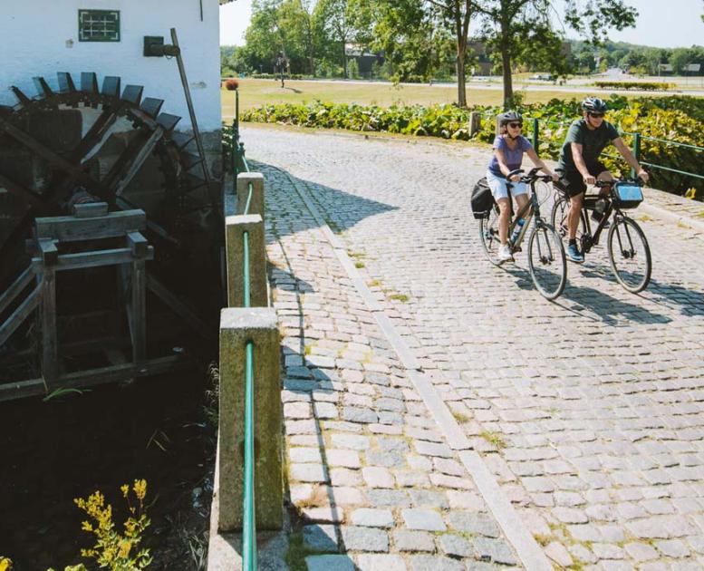 Pärchen fährt Fahrrad an der alten Schlossmühle in Aabenraa